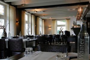 a dining room with tables and chairs and windows at Hotel Brasserie Oud Maren in Maren-Kessel