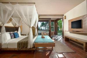 a bedroom with a canopy bed and a television at Jeeva Klui Resort in Senggigi