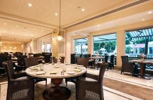 a dining room with a table and chairs and windows at Taj Connemara, Chennai in Chennai