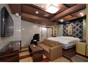 een slaapkamer met een bed, een bank en een tv bij Hotel ShaSha Resort Suma in Kobe