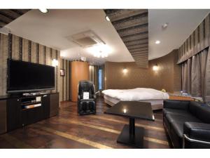um quarto de hotel com uma cama e uma televisão de ecrã plano em Hotel ShaSha Resort Suma em Kobe