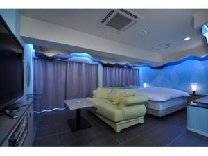 een slaapkamer met een bed, een bank en een televisie bij Hotel ShaSha Resort Suma in Kobe