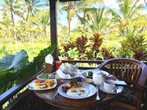 einen Tisch mit Frühstückszutaten auf einem Balkon mit Palmen in der Unterkunft Villa Neyang in Ubud