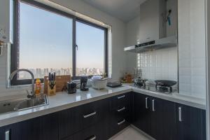 eine Küche mit schwarzen Schränken und einem großen Fenster in der Unterkunft Xi'an Yanta·Yongning Gate· Locals Apartment 00135090 in Xi'an