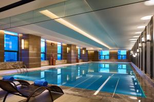 a large swimming pool in a hotel room with chairs at Wanda Realm Qiqihar in Qiqihar