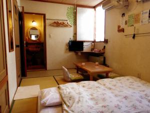 a bedroom with a bed and a table and a window at Pension Yumekukan in Hakodate