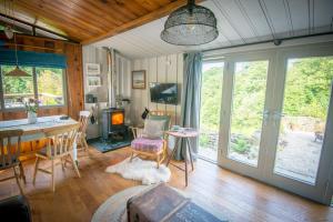 een woonkamer met een tafel en stoelen en een open haard bij Little Kestrel Cabin in Pennal