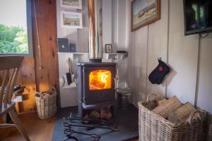 a wood stove in a room with two baskets at Little Kestrel Cabin in Pennal