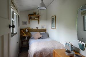 Habitación pequeña con cama y ventana en Little Kestrel Cabin, en Pennal