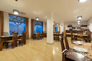 a dining room with tables and chairs and windows at Pensiunea Ecaterina in Berzasca