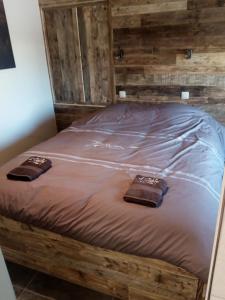 una cama de madera con 2 toallas encima en L'Etable d'Evelyne en Bastogne