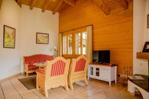 ein Wohnzimmer mit einem Tisch, Stühlen und einem TV in der Unterkunft Apartment Chamonix - GRIWA RENT AG in Grindelwald
