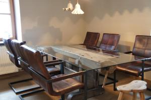 une salle à manger avec une table en verre et des fauteuils en cuir dans l'établissement Design Apartment Villa Anna Kitzbühel, à Kitzbühel