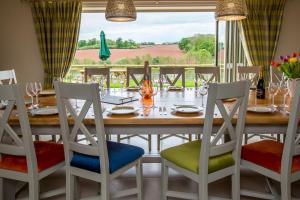 a dining room table with chairs and a large window at The Dinney Holiday Cottages in Bridgnorth