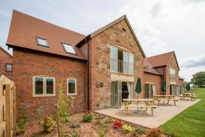 a brick house with picnic tables in the courtyard at The Dinney Holiday Cottages in Bridgnorth
