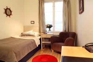 Hotell Uddewalla في أوديفالا: غرفة نوم بسرير وكرسي ونافذة