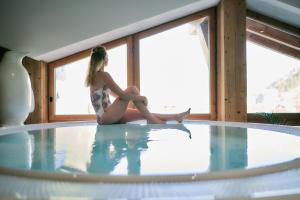 a woman sitting on a tub in a swimming pool at Hôtel Avancher in Val-d'Isère