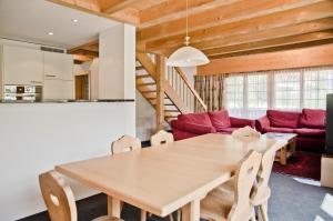 comedor con mesa y sofá rojo en Apartment Eiger - GRIWA RENT AG, en Grindelwald