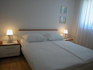 a bedroom with a bed with two nightstands and two lamps at Apartments & Rooms Luna in Bol
