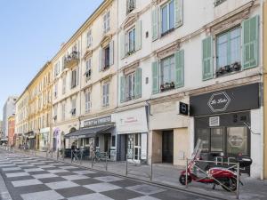 a scooter parked in front of a building on a street at Welkeys - Delille Apartment in Nice