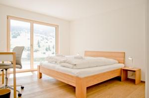 un letto in una camera con una grande finestra di Chalet Eigerlicht - GRIWA RENT AG a Grindelwald