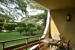 eine Veranda mit einem Tisch und Stühlen auf dem Balkon in der Unterkunft Hotel Club du Lac Tanganyika in Bujumbura