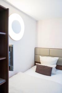 - une chambre avec un lit blanc et un oreiller marron dans l'établissement BASE II - Das Bed & Breakfast bei Basel (Lörrach), à Lörrach