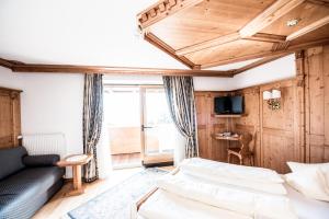 - un salon avec un canapé et une télévision dans l'établissement Hotel Enzian Genziana, à Alpe di Siusi
