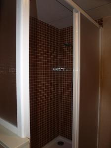 y baño con ducha y azulejos marrones. en Apartaments Geminis, en Cambrils