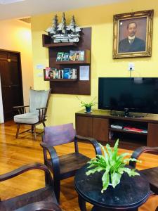 a living room with a flat screen tv and chairs at Phuket Sunny Hostel in Phuket Town