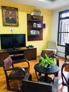 a living room with a tv and a table and chairs at Phuket Sunny Hostel in Phuket Town
