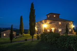 un grande edificio in pietra con luci accese di notte di Agriturismo Ragoncino a Laiatico