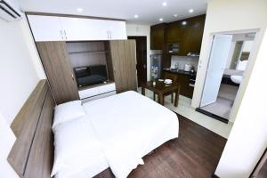 a bedroom with a white bed and a kitchen at Granda Legend Apartment in Hanoi