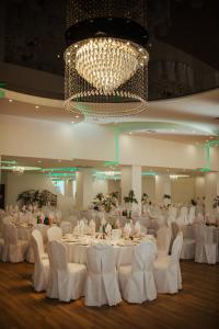 a banquet hall with white tables and chairs and a chandelier at Centrum Bankietowo - Hotelowe "Perła" in Leżajsk