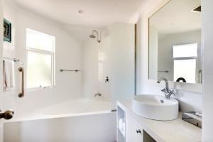 a bathroom with a tub, sink and mirror at Seashells Broome in Broome