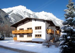 a building with a snow covered mountain in the background at Alpenapart Zell in Längenfeld