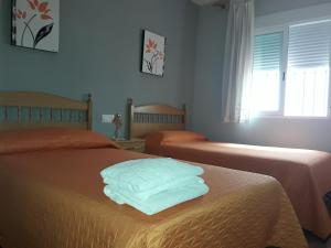 una camera con due letti con lenzuola bianche e una finestra di Alojamiento Vacacional Inma parking gratis a Cazorla