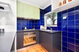 a kitchen with blue tiles on the walls and counters at Beachfront Apartment in Melbourne