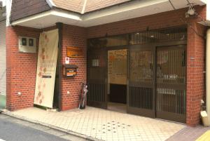 a brick building with doors with a dog standing outside at Guest House Kyoto Inn in Kyoto