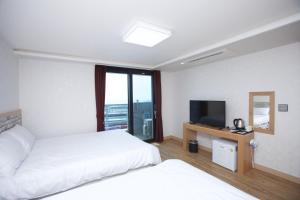 a hotel room with two beds and a television at Jeju Moseulpo Hotel in Seogwipo