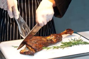 a person cutting a piece of meat with a knife at Herods Dead Sea – A Premium Collection by Fattal Hotels in Neve Zohar