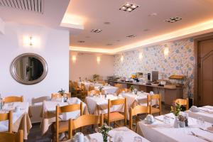 a restaurant with white tables and chairs and a counter at Panormo Beach Hotel in Panormos Rethymno