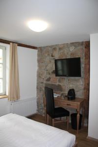 a hotel room with a desk and a tv on a stone wall at Hotel Hahnmühle 1323 in Coburg