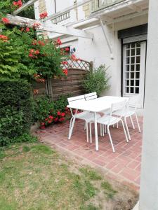 カブールにあるCabourg centre, F4 avec jardin, 100m de la merの白いテーブルと椅子が備わるレンガ造りのパティオ