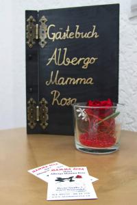 una mesa con un letrero y un tazón de rosas rojas en Hotel Albergo Mamma Rosa en Wunsiedel