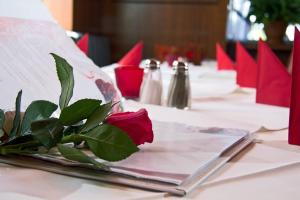 a table with a red rose on top of it at Hotel Albergo Mamma Rosa in Wunsiedel