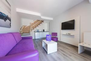 un salon avec un canapé violet et une télévision dans l'établissement eó Maspalomas Resort, à Maspalomas