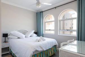 1 dormitorio con 1 cama blanca y 2 ventanas en La Mustique 21, en Ballito