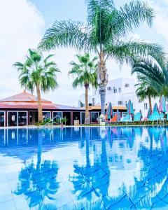 a large swimming pool with palm trees in front of a building at Yiannis Manos Hotel Resort in Malia