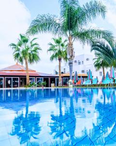 uma grande piscina com palmeiras em frente a um edifício em Yiannis Manos Hotel Resort em Malia